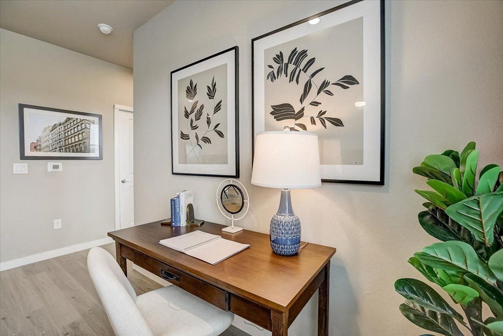 an office with a desk and a lamp and pictures on the wall