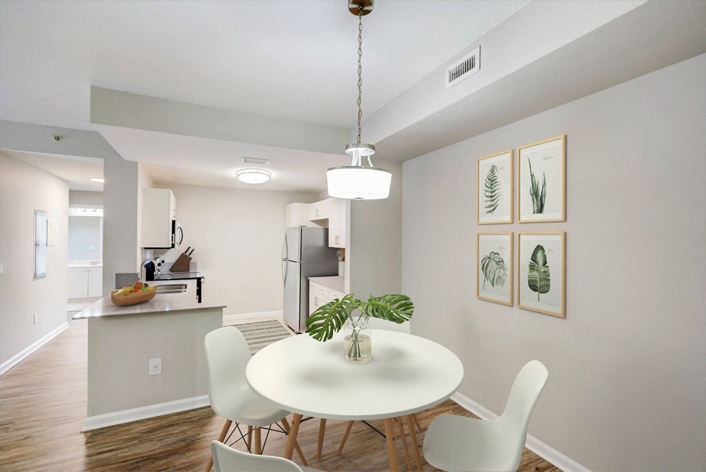 a dining room with a white table and chairs and a kitchen