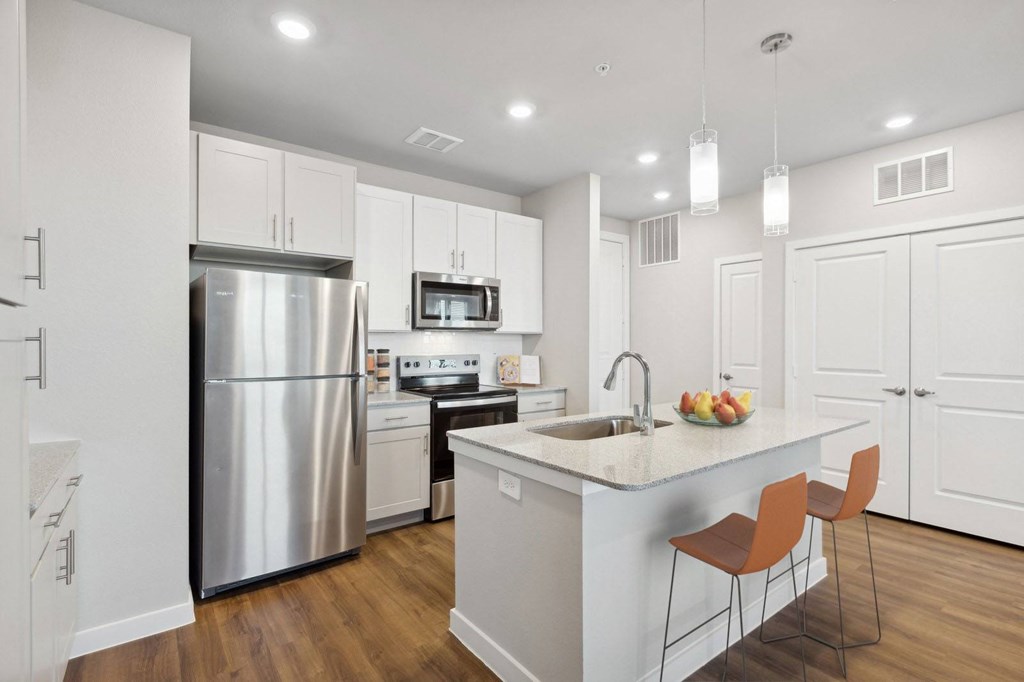 A modern kitchen with a stainless steel refrigerator, microwave, and wooden floors.