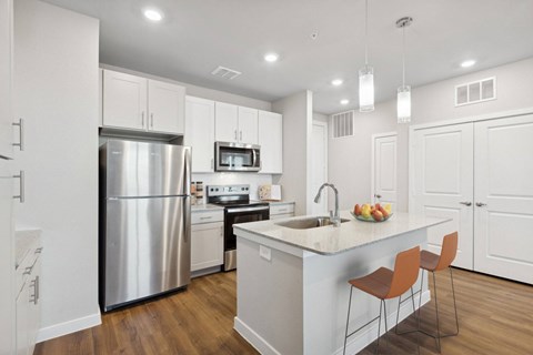 A modern kitchen with a stainless steel refrigerator, microwave, and wooden floors.