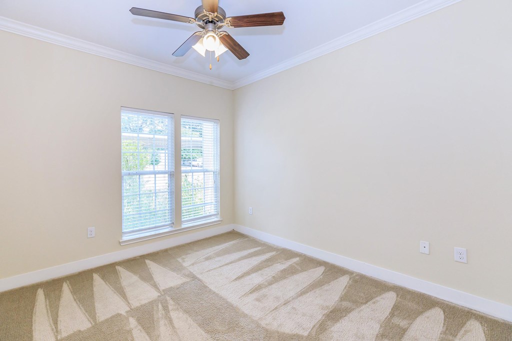 A room with a ceiling fan and a carpet on the floor.