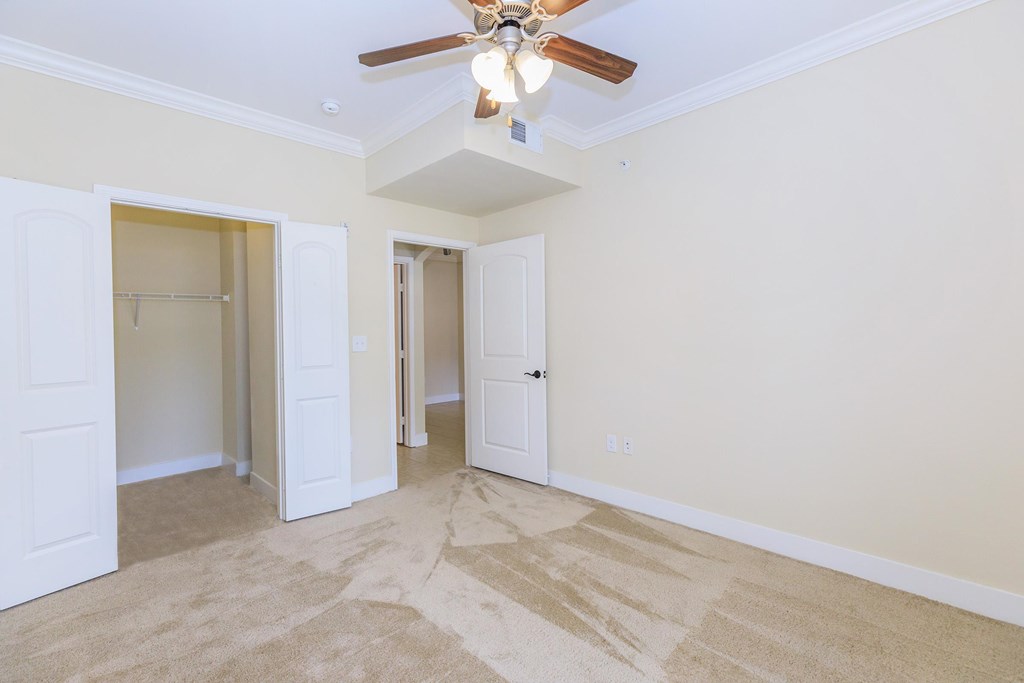 A room with a ceiling fan and carpeted floor.