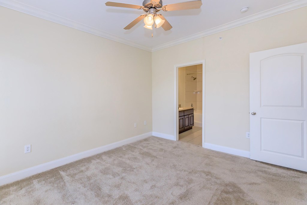 A room with a ceiling fan and carpeted floor.