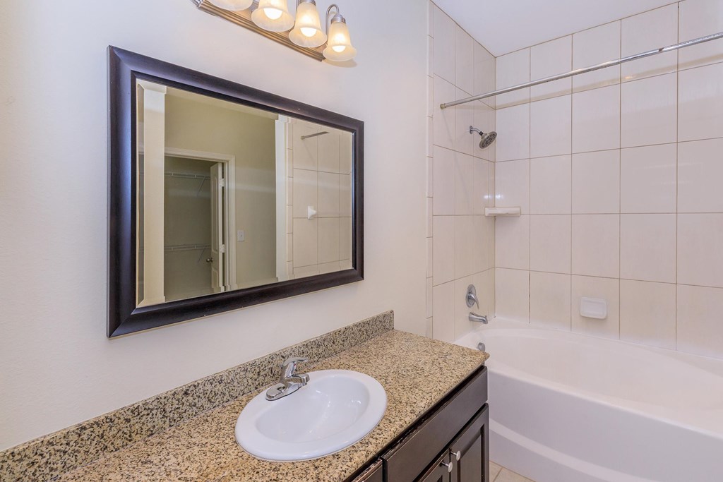 A bathroom with a sink, mirror, and bathtub.