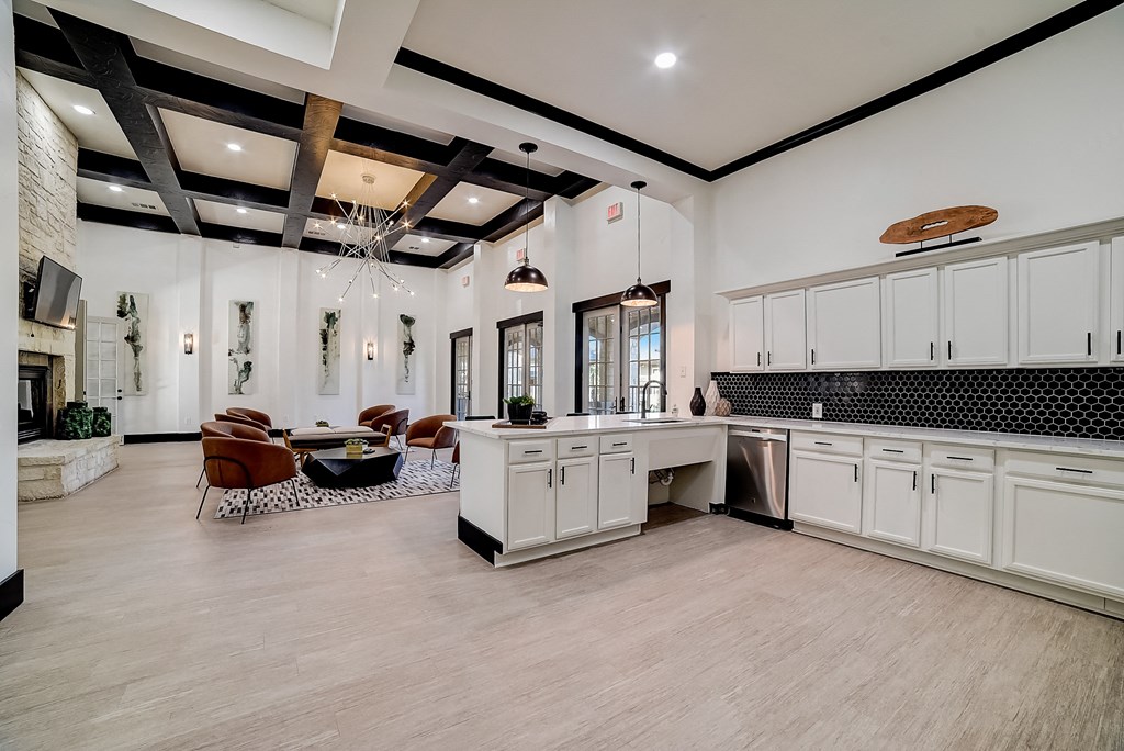 a large kitchen with white cabinets and a living room with a table and chairs