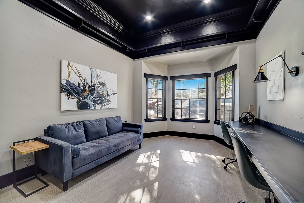 the living room has a blue couch and a desk and a window