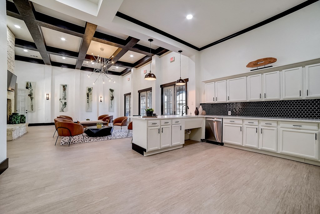 an open kitchen and living room with white cabinets and a white counter top