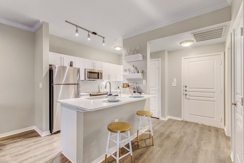 a kitchen with an island with stools and a refrigerator