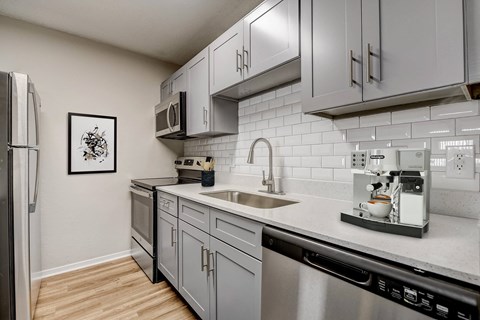 an apartment kitchen with stainless steel appliances and white cabinets