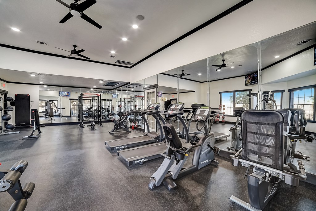 a gym with cardio equipment and mirrors on the wall