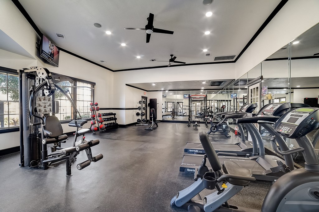 a gym with weights and cardio machines and a ceiling fan