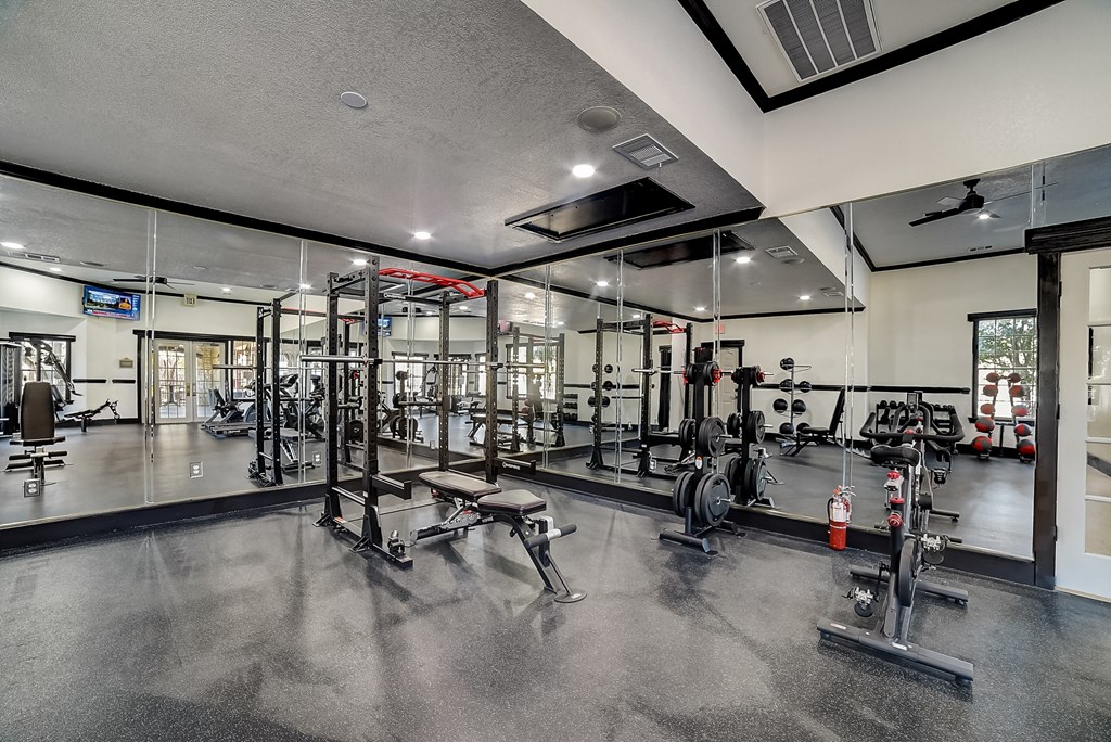 a gym with weights and cardio equipment on the floor and glass walls