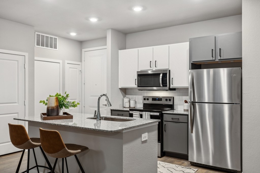A modern kitchen with a stainless steel refrigerator, microwave, and oven.