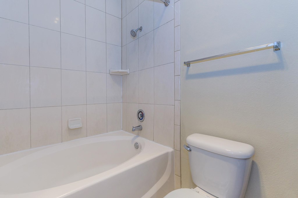 A white toilet sits next to a bathtub in a bathroom.