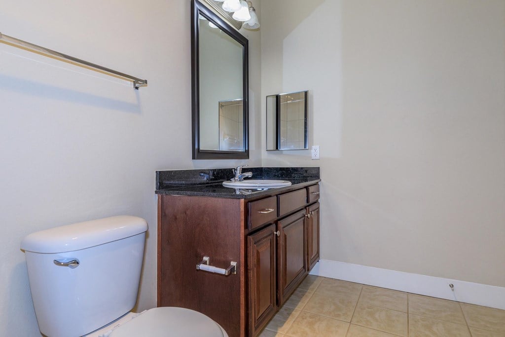 A bathroom with a toilet, sink, and mirror.