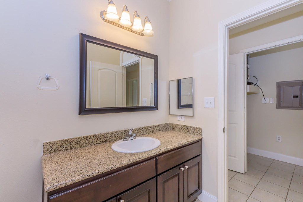 A bathroom with a sink, mirror, and light fixture.