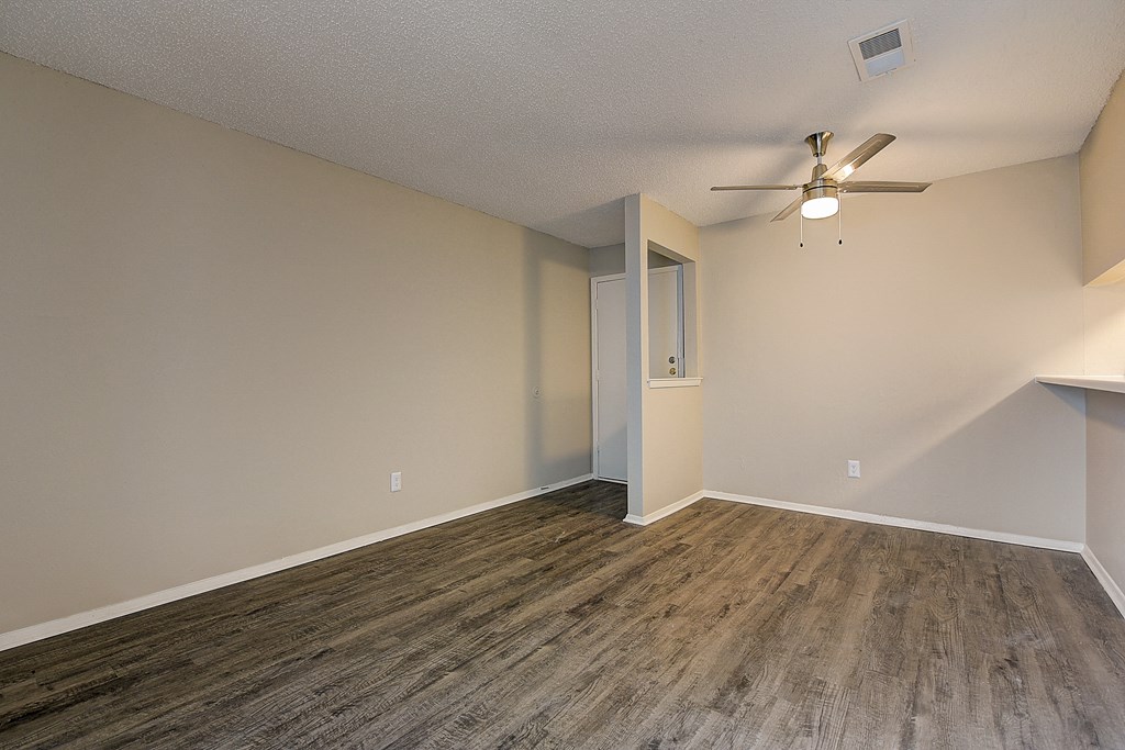 an empty living room with wood flooring and a ceiling fan