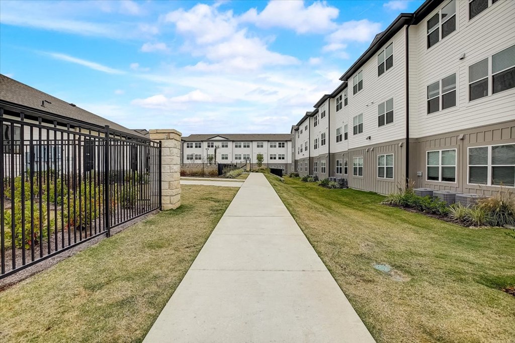the walkway between two apartment buildings with a gated sidewalk