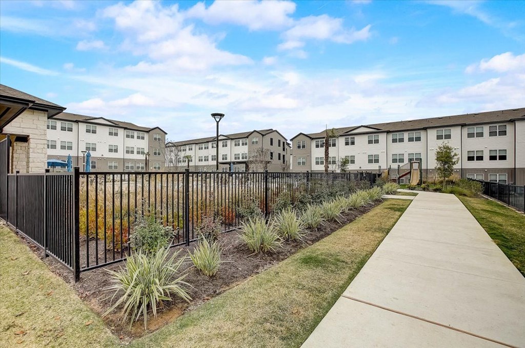 the view of a sidewalk and a fence with apartment buildings