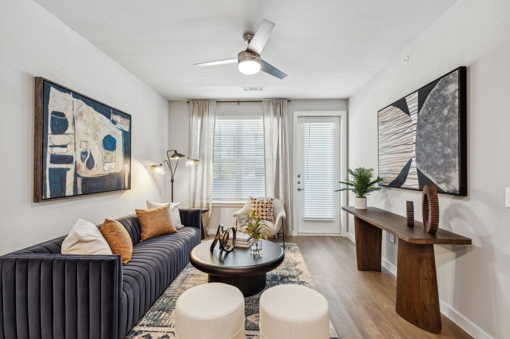 A living room with a dark blue couch, a coffee table, and a ceiling fan.