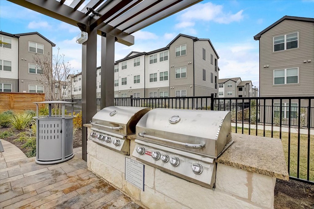 two gas bbqs on a patio with apartment buildings