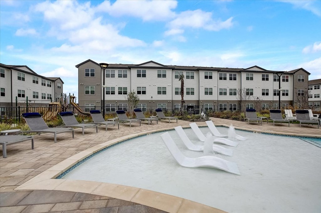 a swimming pool with a white bench in front of some apartment buildings