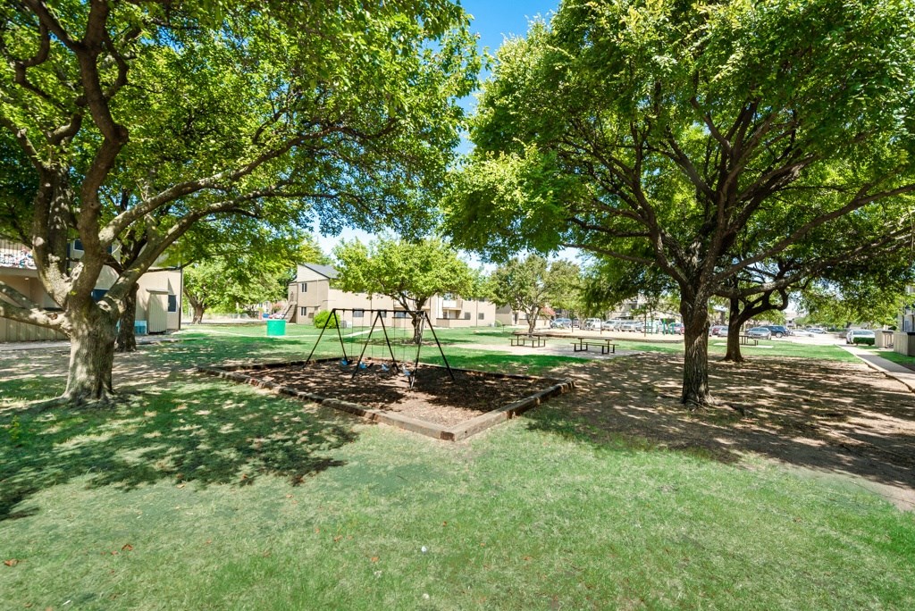 a playground with trees and a swing in a park