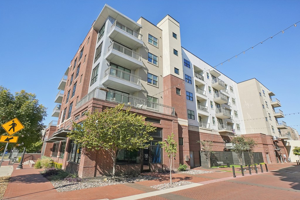 A multi-story apartment building with a yellow pedestrian crossing sign in front.