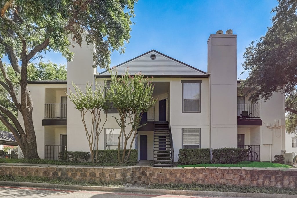 an apartment building with stairs and trees in front of it