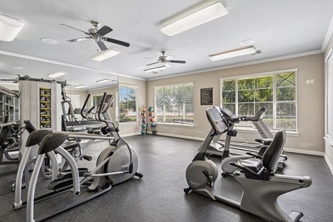 A spacious gym with a variety of exercise equipment and a fan.