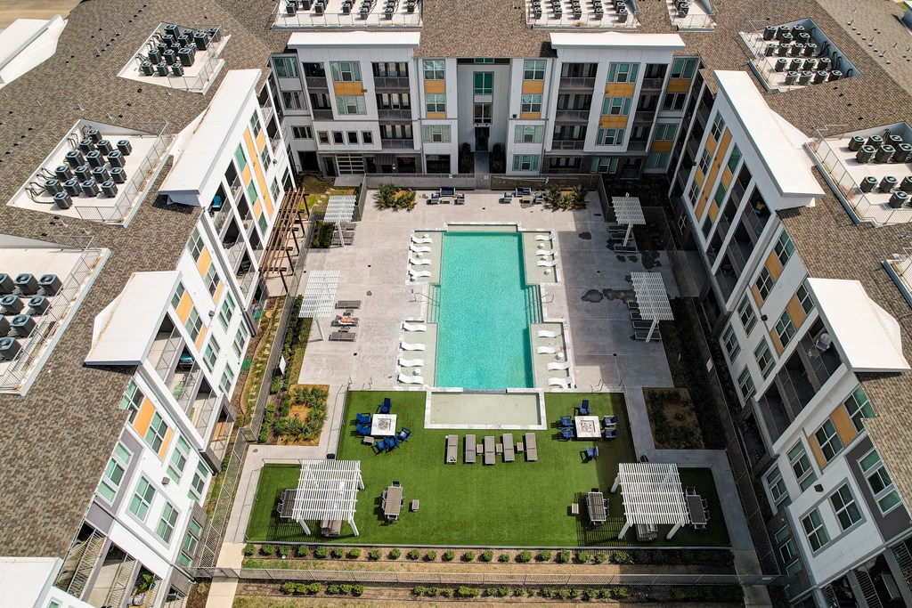an aerial view of a building with a pool and lawn