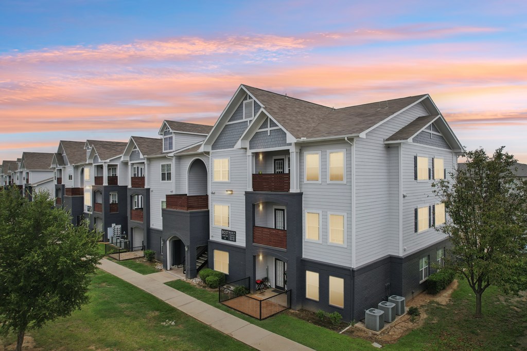 A row of modern townhouses with a sunset sky in the background.