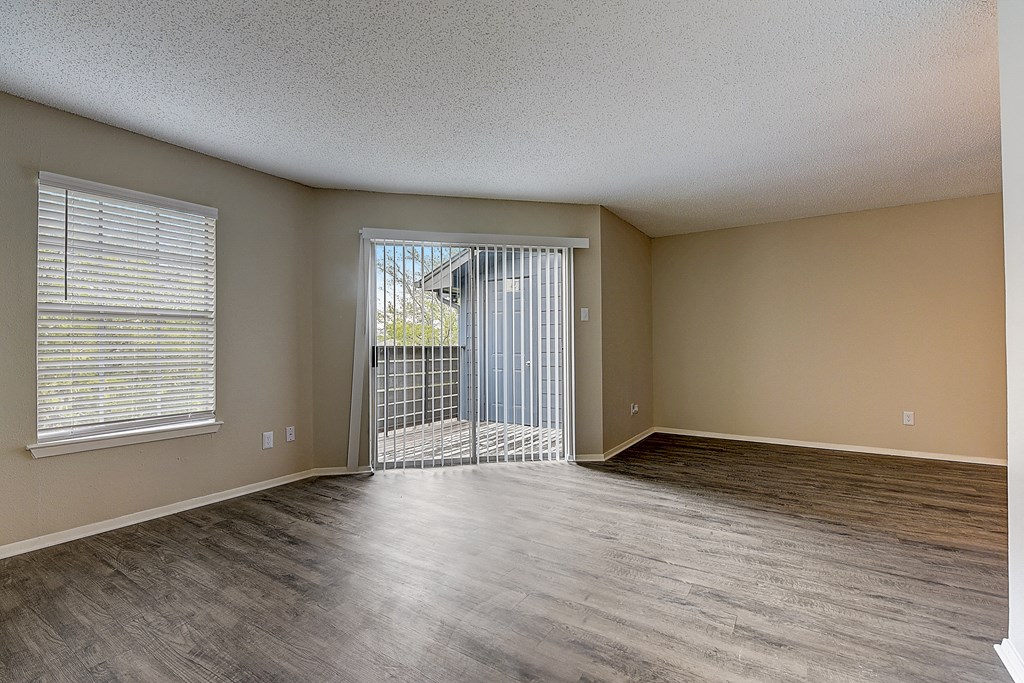 an empty living room with a door to a balcony