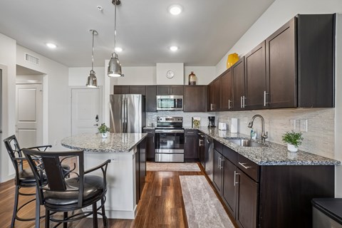A kitchen with dark brown cabinets and a granite countertop.