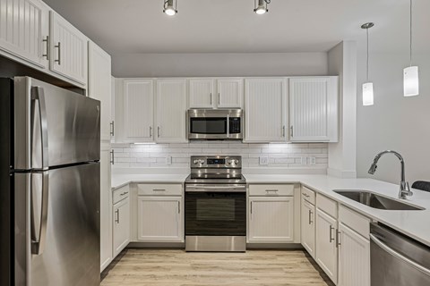 A modern kitchen with white cabinets and stainless steel appliances.