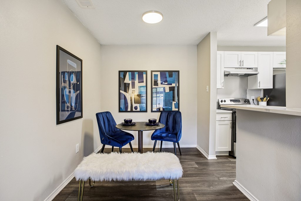 A dining area with a white furry bench and blue chairs.