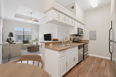 A kitchen with white cabinets and a wooden table.