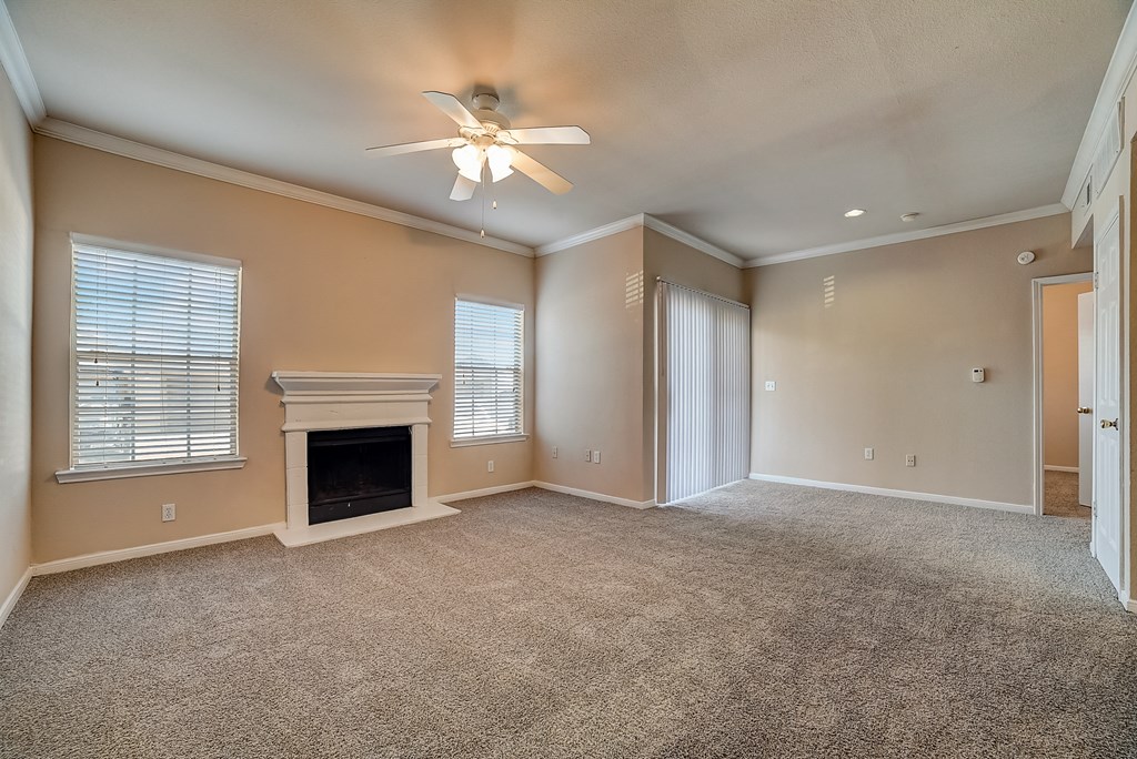 an empty living room with a fireplace and a ceiling fan