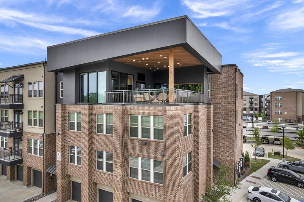 a brick apartment building with a balcony and a roof top terrace