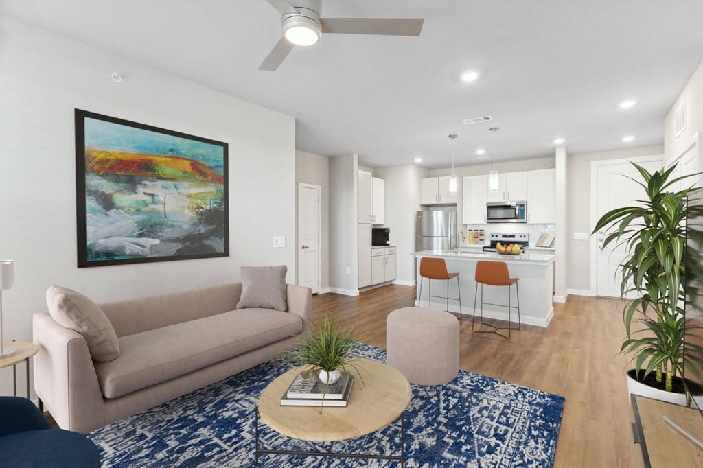 A living room with a beige couch, a coffee table, and a painting on the wall.