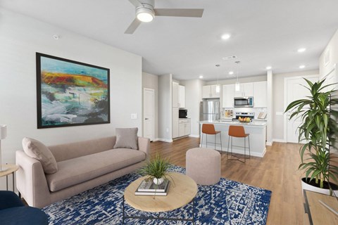 A living room with a beige couch, a coffee table, and a painting on the wall.