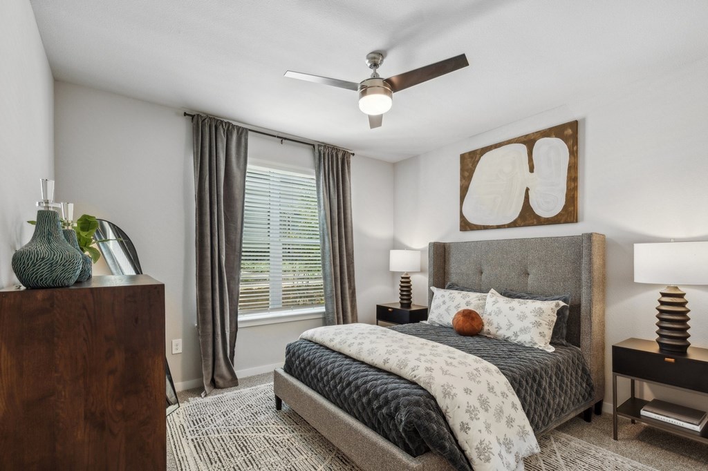 A bedroom with a large bed and a ceiling fan.