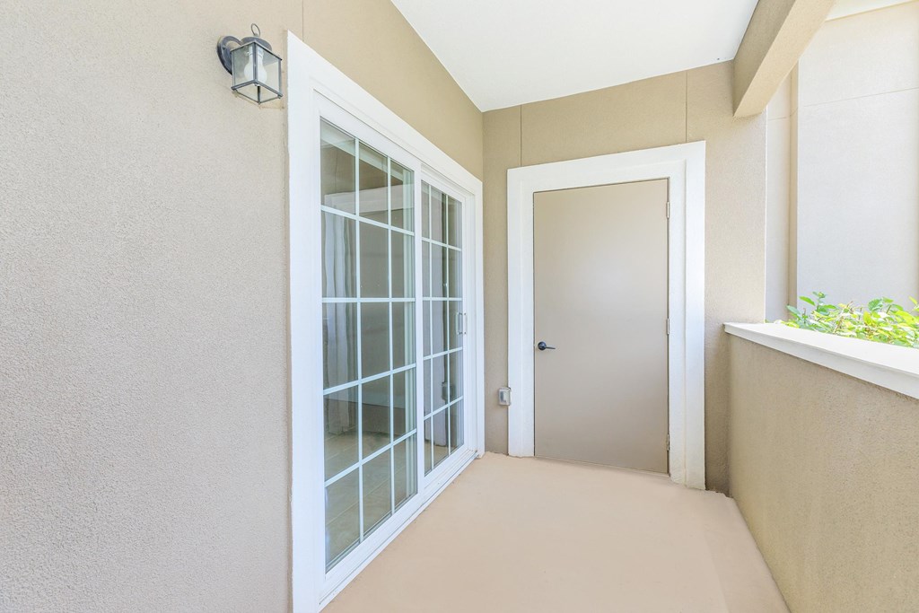 A hallway with a glass door and a white door.
