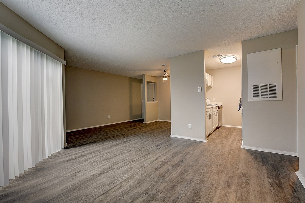 an empty living room and kitchen with wood flooring
