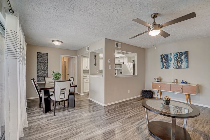 a living room and dining room with a table and a ceiling fan