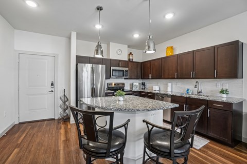 A kitchen with a granite countertop and a stainless steel refrigerator.