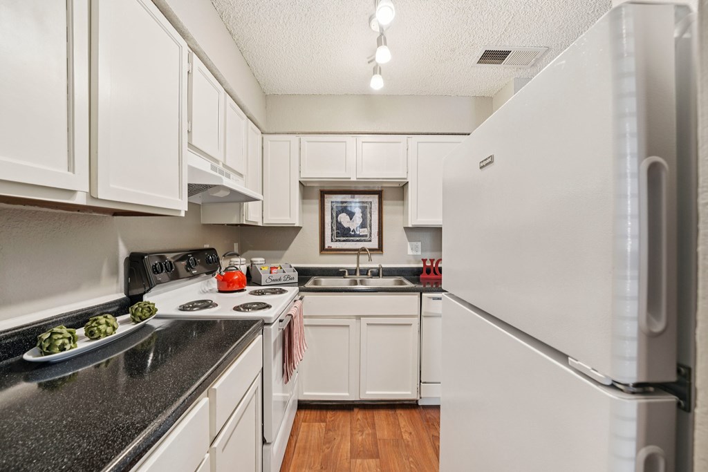 A kitchen with white cabinets and a fridge.