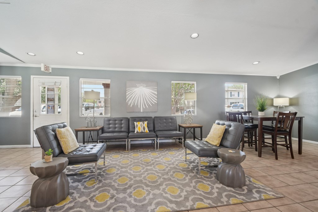 A grey sofa with yellow pillows is in the middle of a room with a grey carpet.