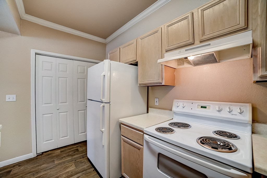 an empty kitchen with white appliances and a refrigerator
