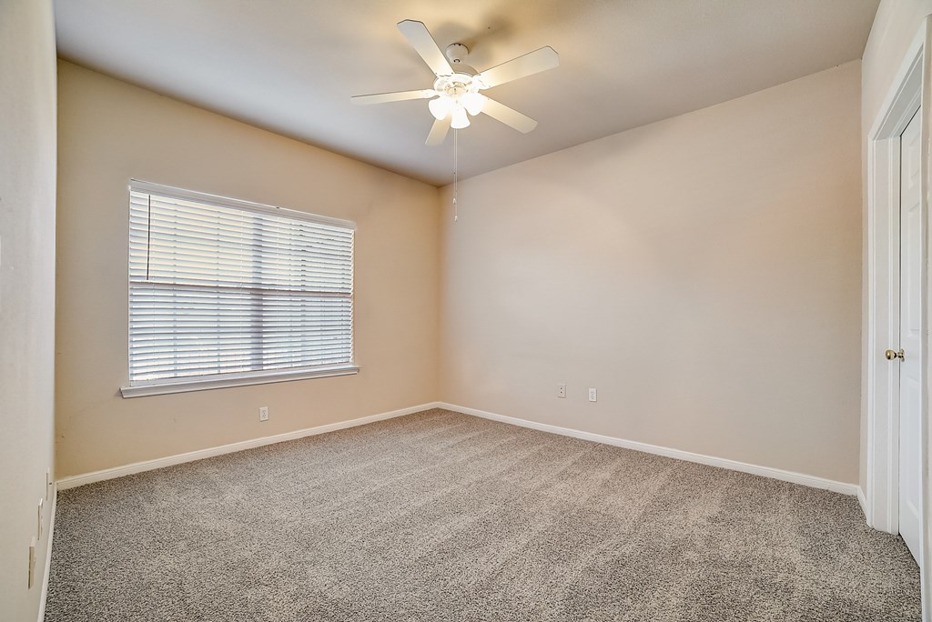 an empty room with carpet and a ceiling fan